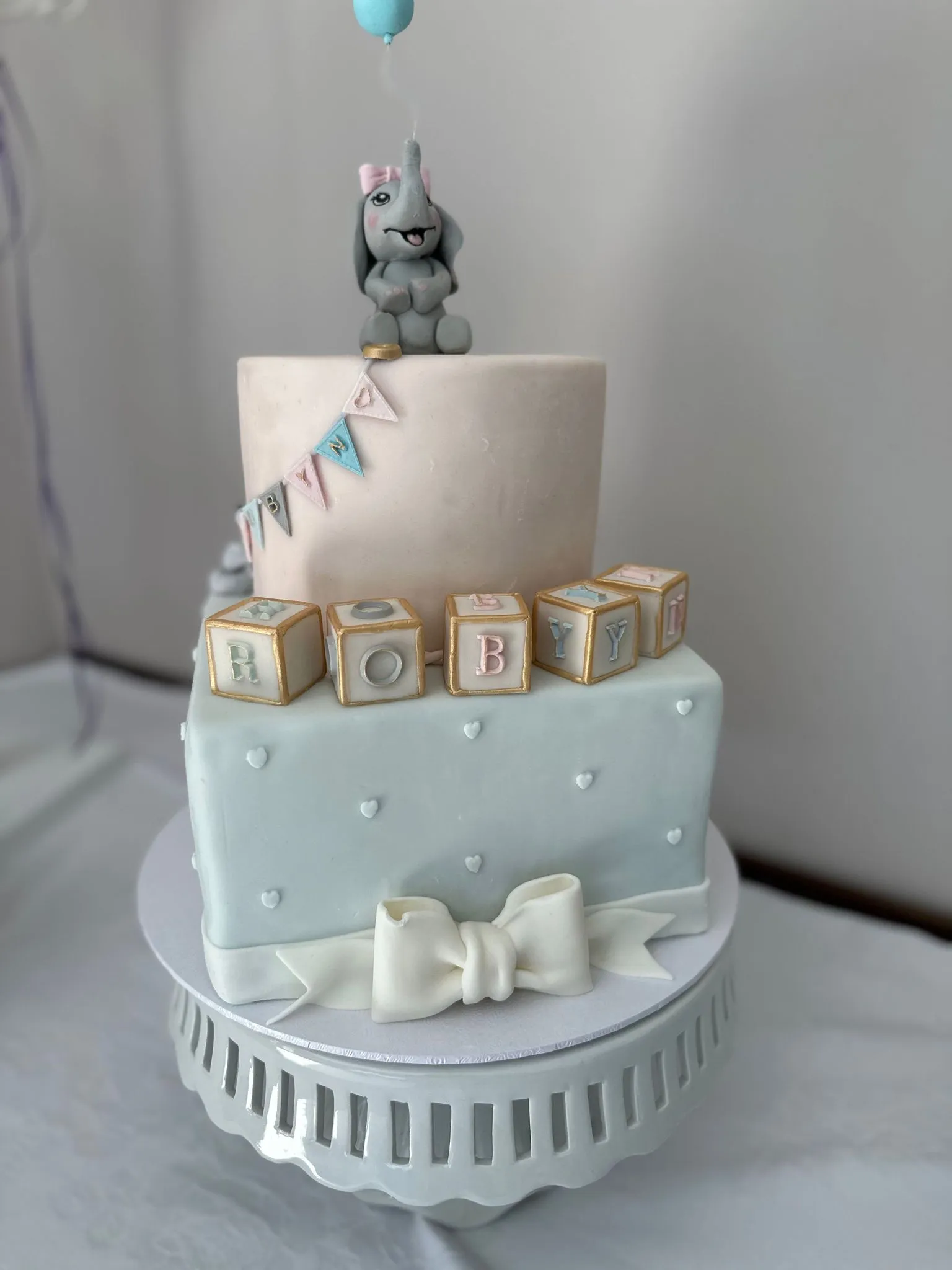 Christening cake with blue and pink elephant topper and delicate details