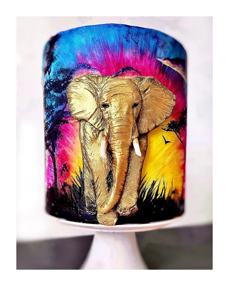 Gold sculpted elephant emerging from a hand-painted African sunset cake