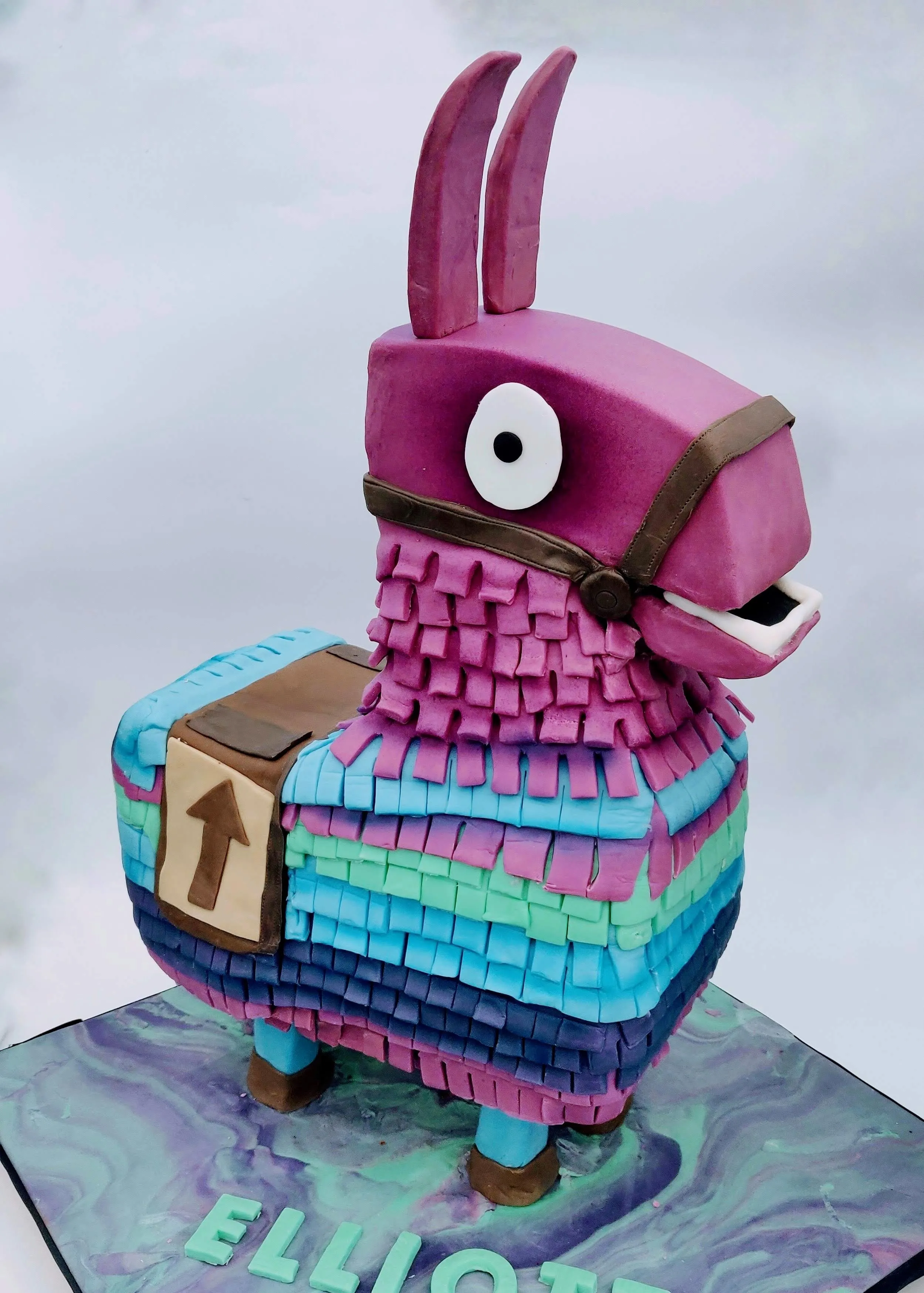 Sculpted Fortnite Loot Llama pinata cake in purple, blue and pink standing upright on a marbled base