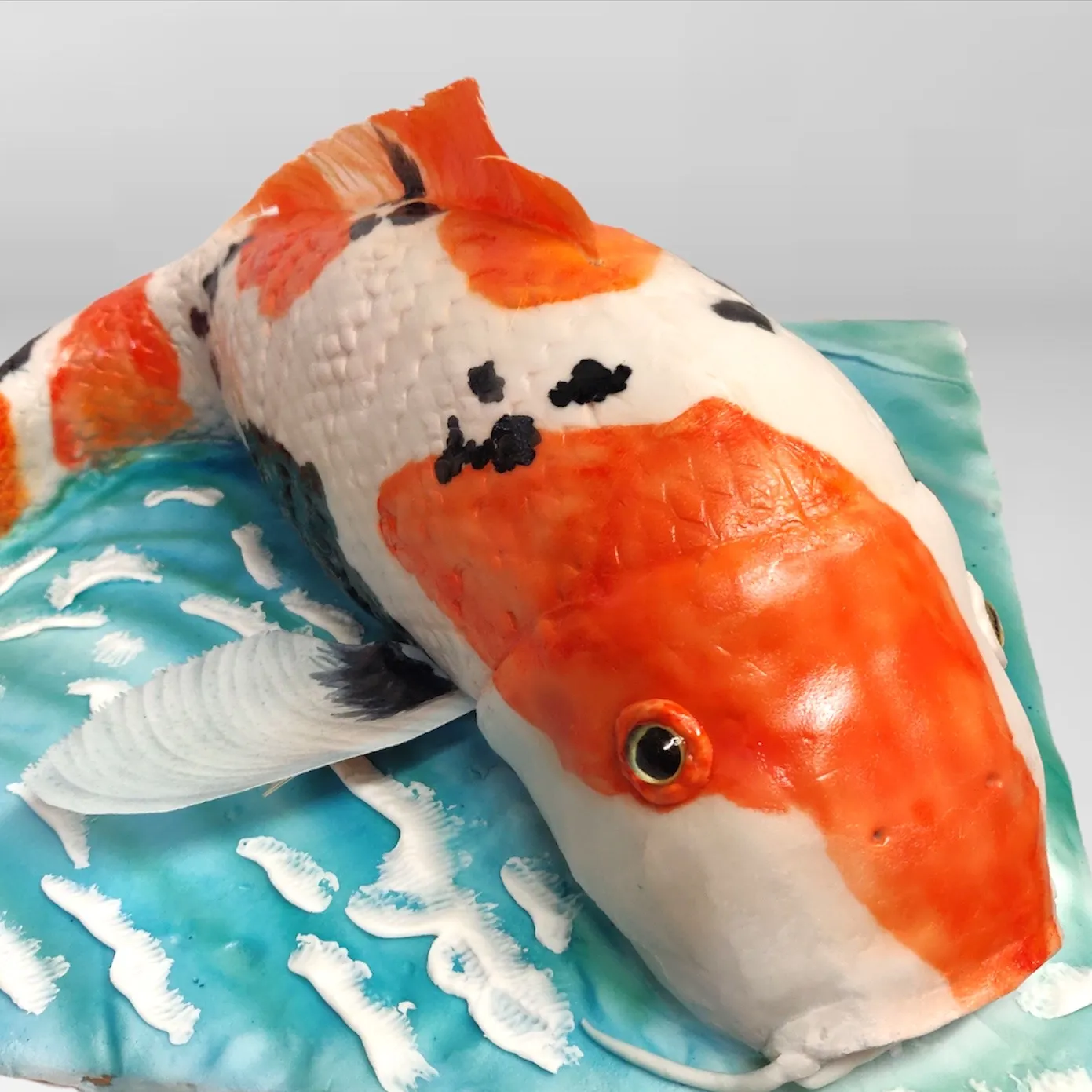 Close-up of sculpted koi fish cake showing detailed hand-painted orange and white scales