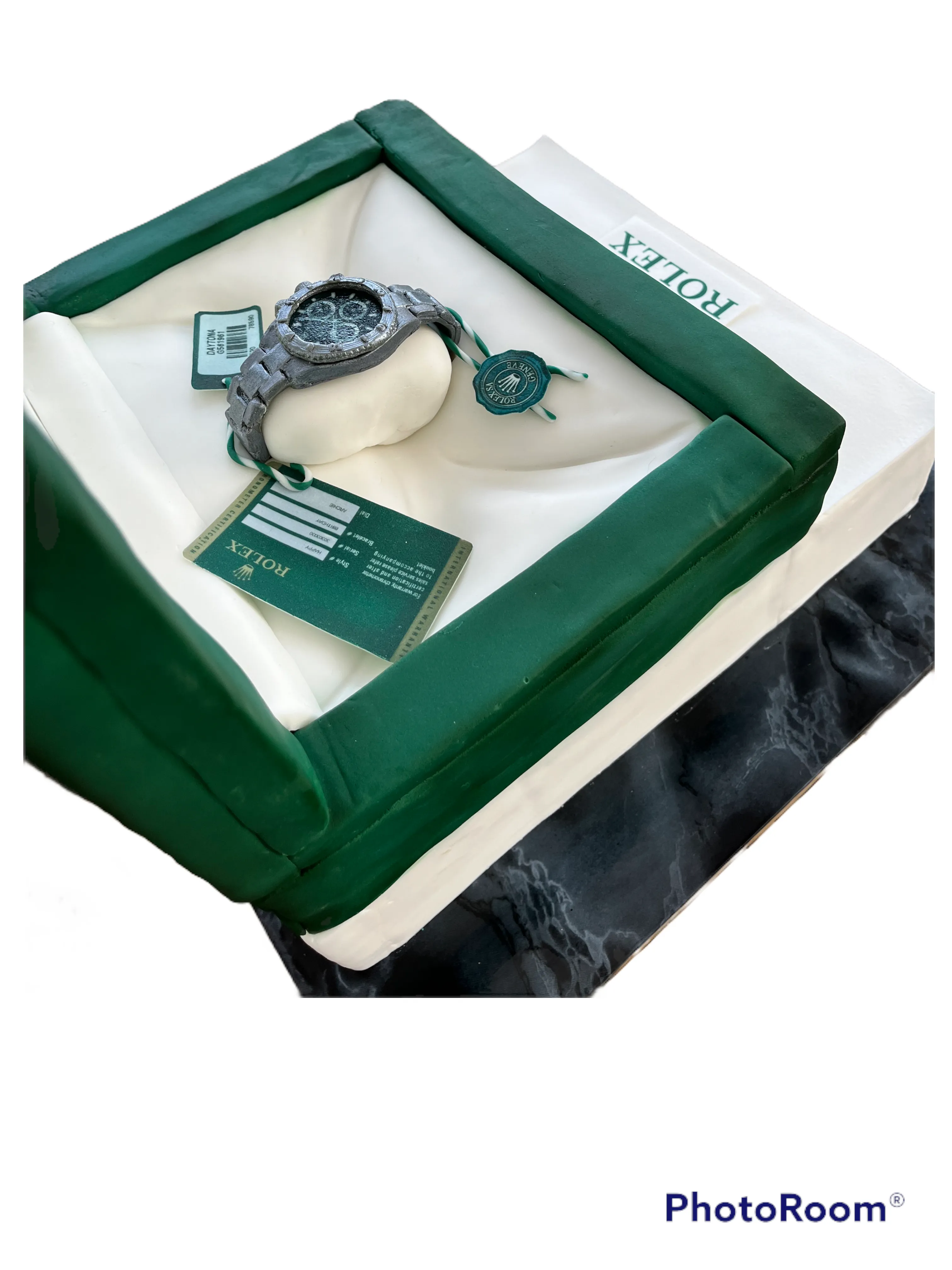 Top-down view of sculpted Rolex watch box cake showing watch face and green case detail
