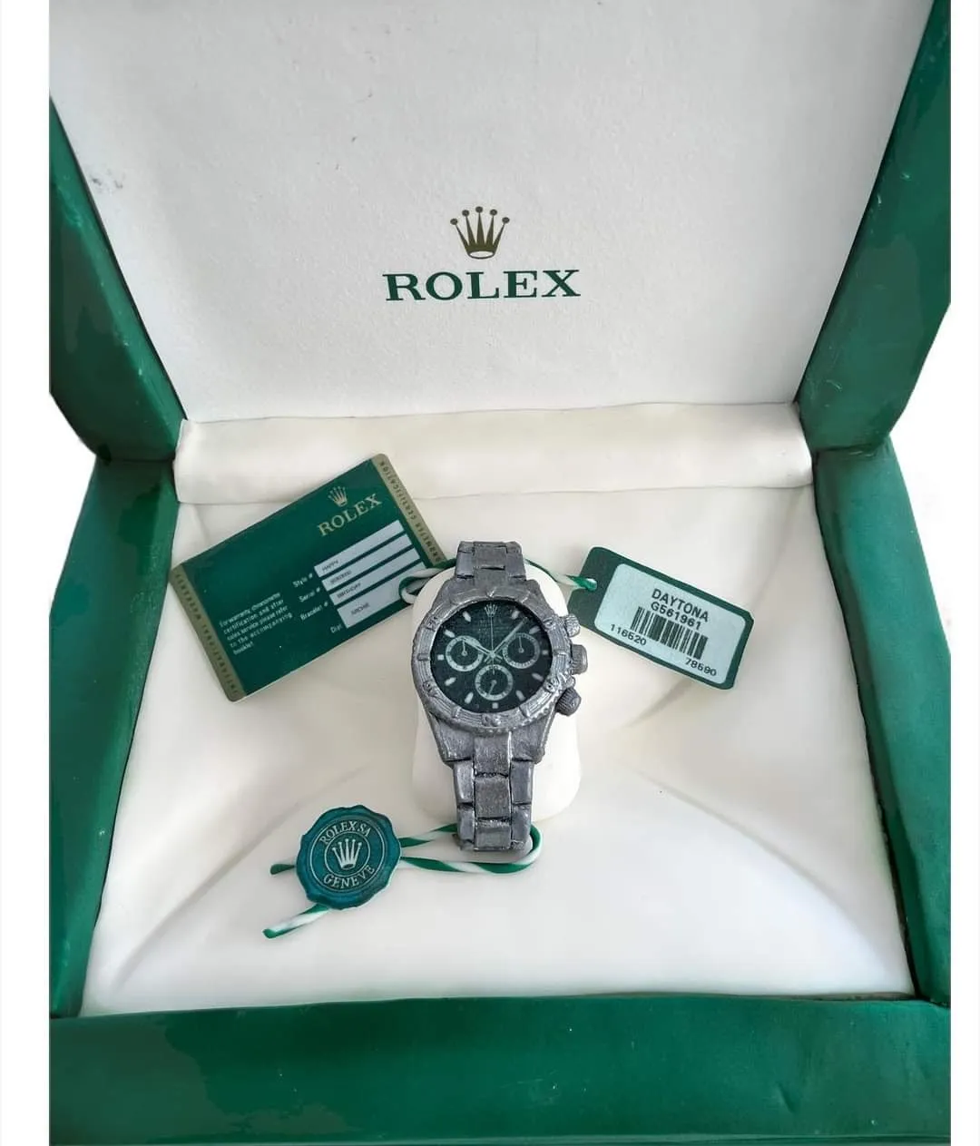 Close-up angle of sculpted Rolex Daytona watch and box showing face detail