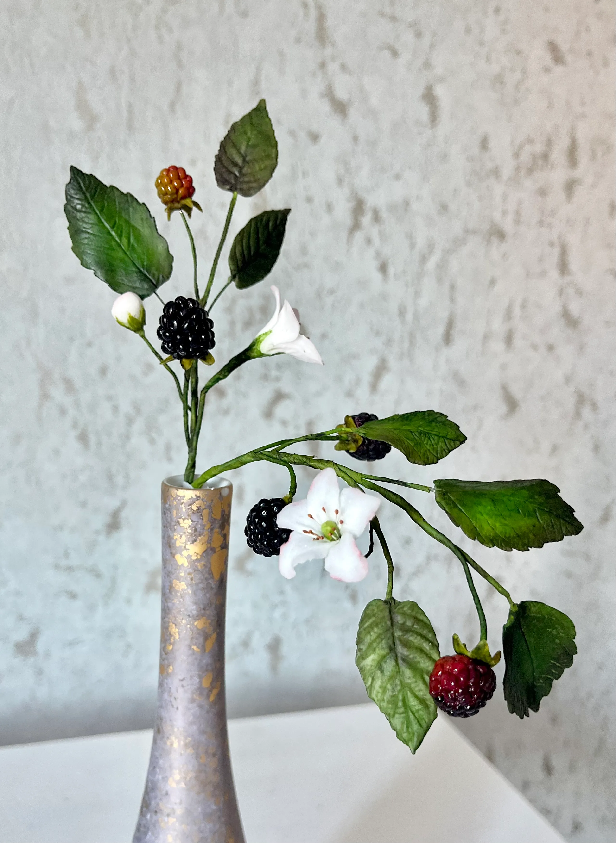 Three individual single-tier cakes on metal stands with cream dahlias and burgundy roses, styled with pink taper candles