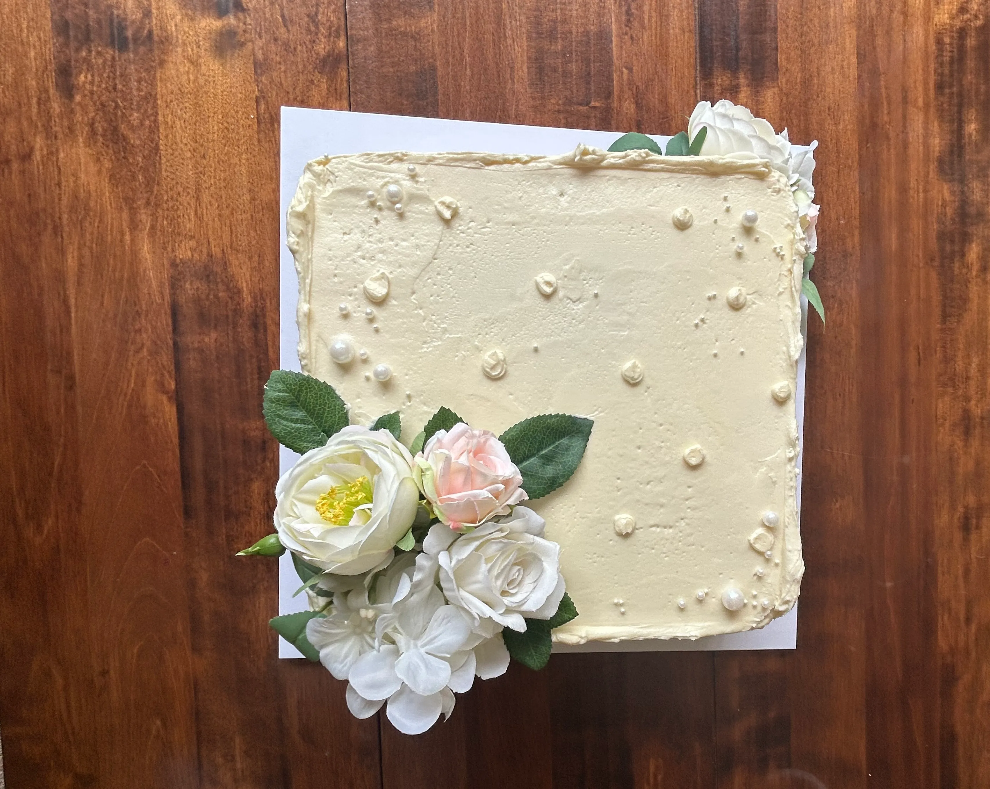 Overhead view of square buttercream cake with white piped roses