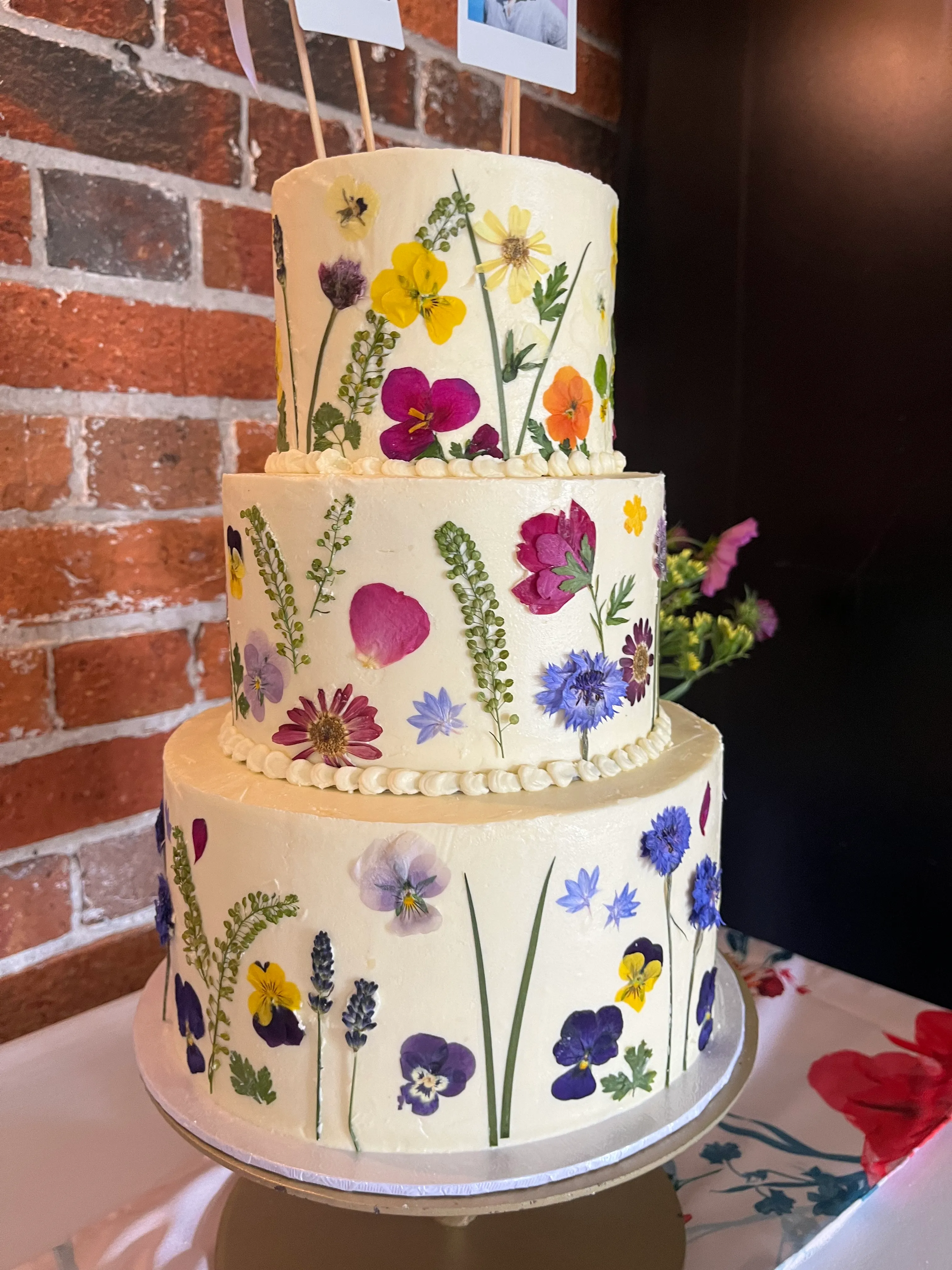 Three-tier cake with dramatic oversized sugar peonies on top and gold brush stroke details