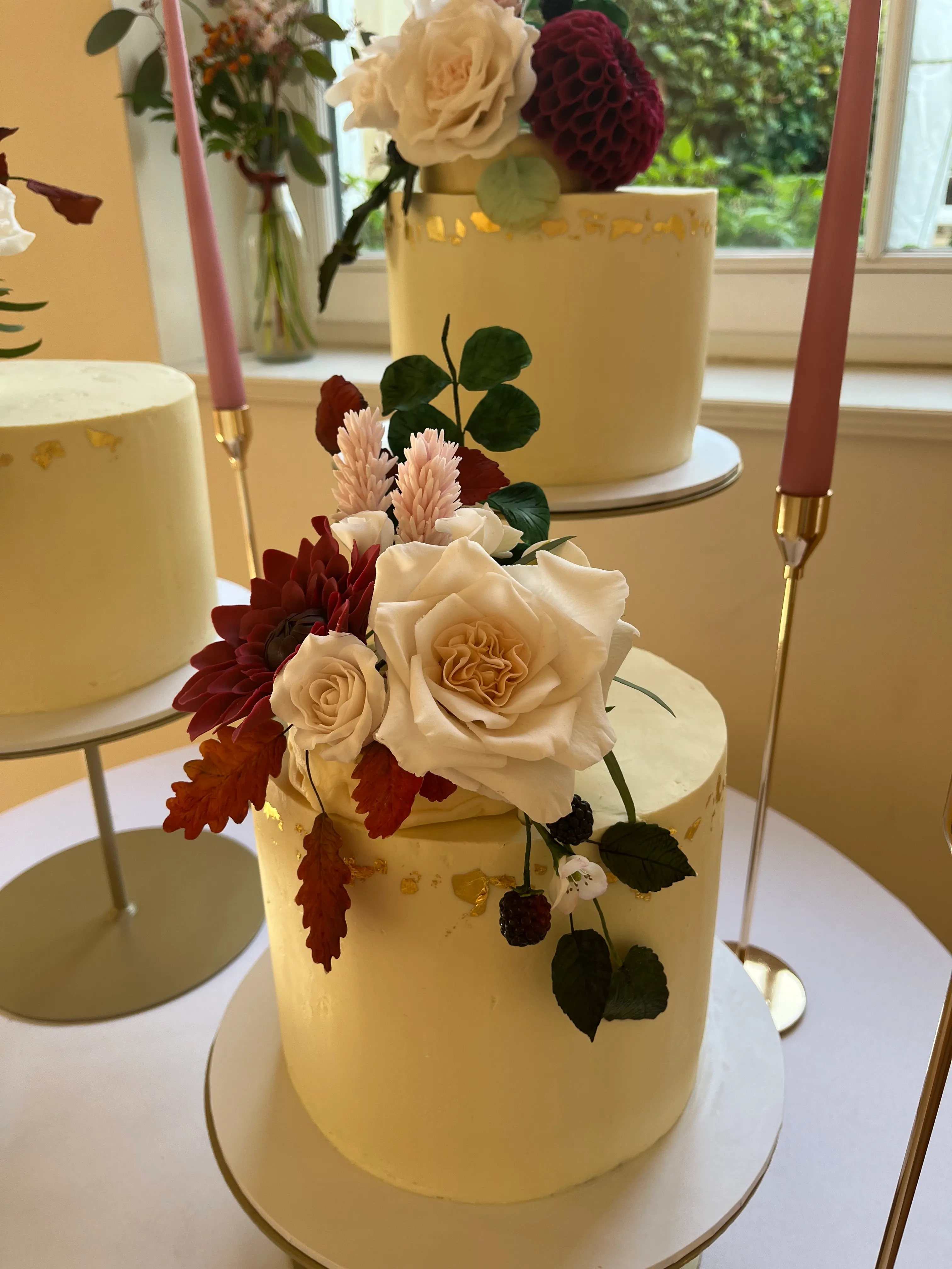 Trio of wedding cakes with burgundy dahlias and cascading foliage